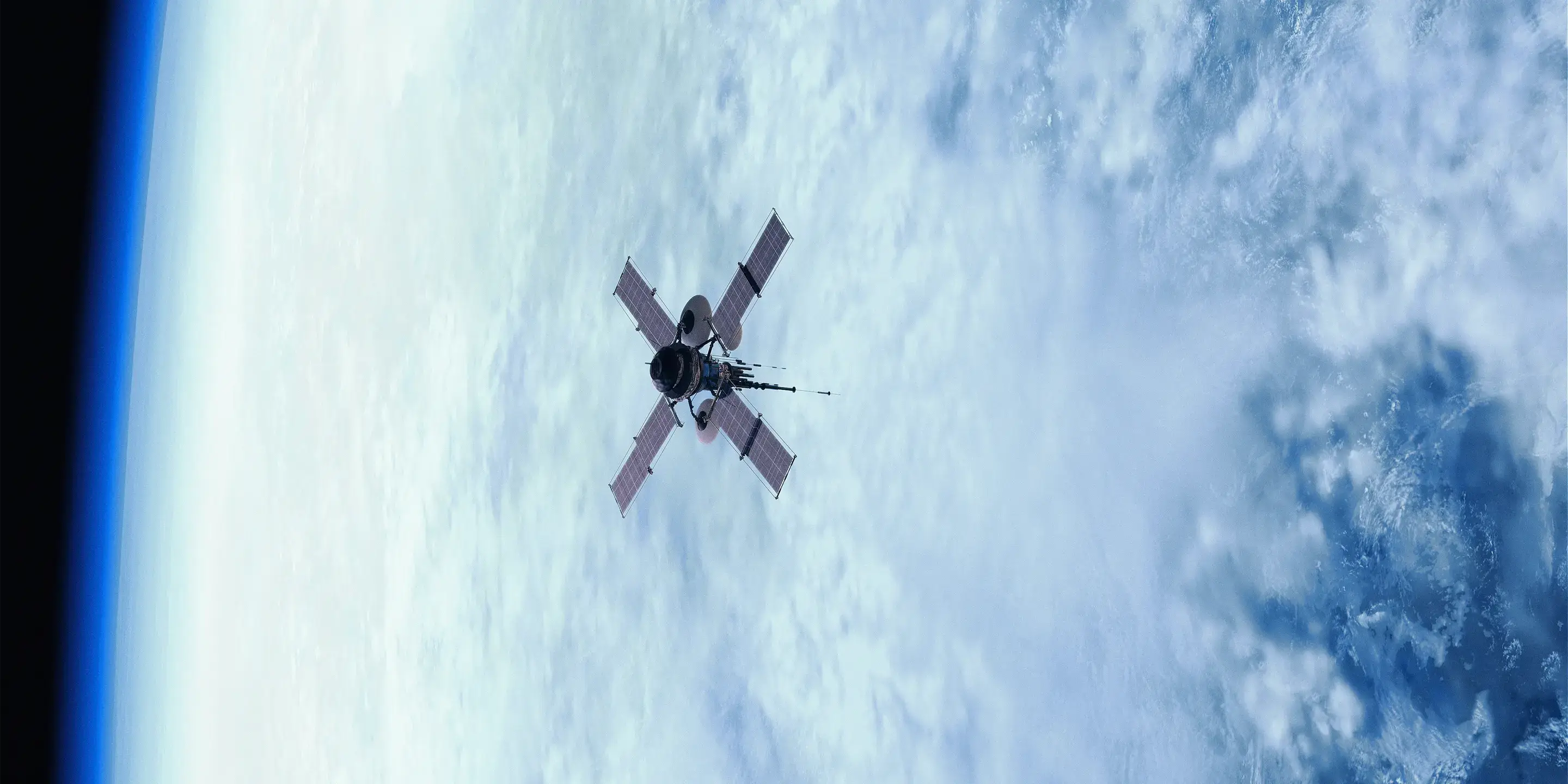 Satellite orbiting earth, with solar panels extended on either side, against a backdrop of clouds and the blue curve of the planet's atmosphere.